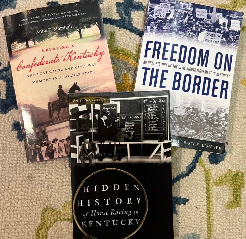 Three books centered on the complexities of Kentucky, which was a border state that stayed in the Union while also supporting slavery. Left is "Creating a Confederate Kentucky." Center is "Hidden History of Horse Racing in Kentucky." Right is "Freedom on the Border: An Oral History of the Civil Rights Movement in Kentucky."